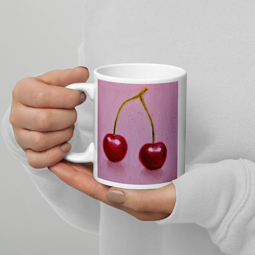 Red cherries on a pink background on a white mug